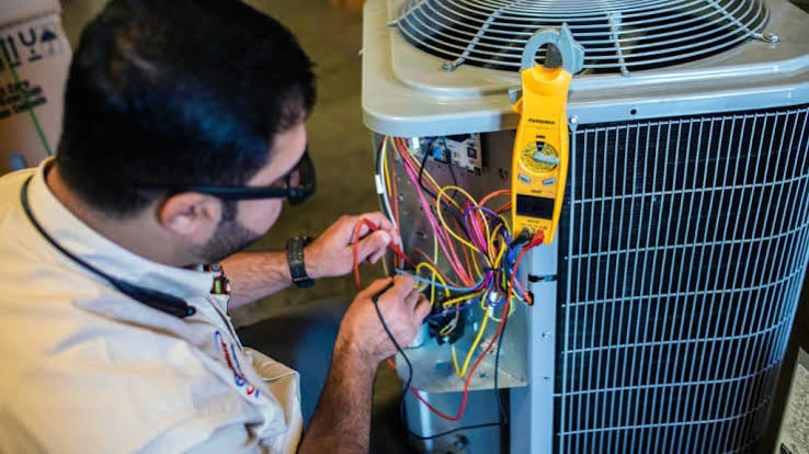 Technician testing an air conditioner’s electrical components with a meter