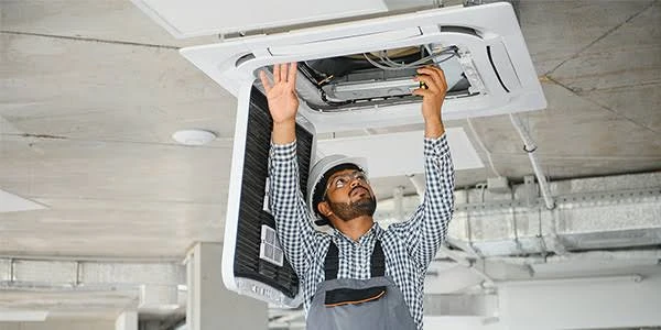 Technician servicing a ceiling-mounted air conditioning unit