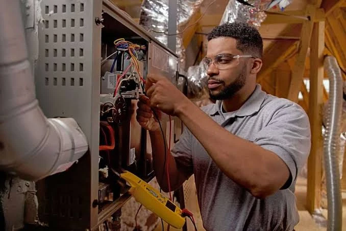 Technician inspecting wiring inside a residential furnace